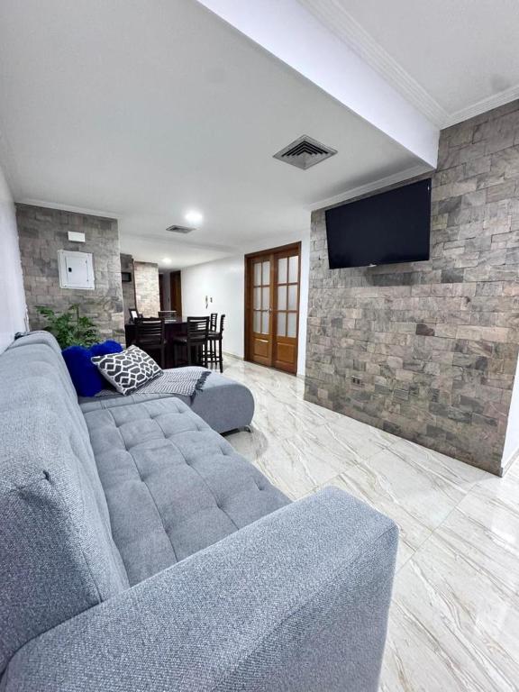 Una sala de estar con un sofá azul y una pared de piedra. en Entire home in Lechería, Venezuela, en El Morro de Barcelona