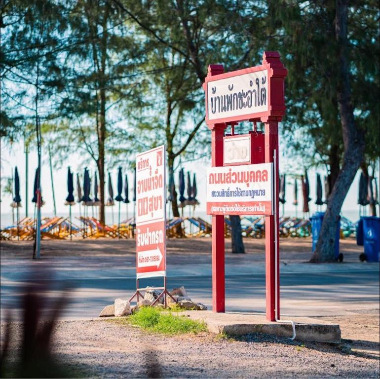 a red telephone booth with two signs on a street at บ้านพักหน้าหาดชะอำใต้ in Ban Sahakham