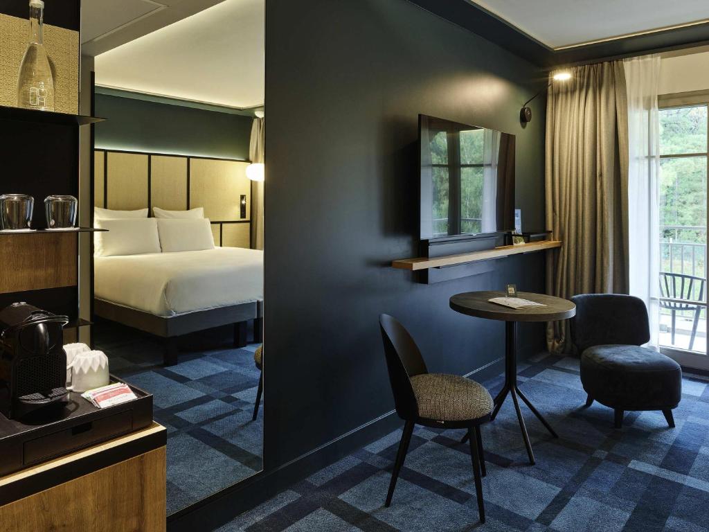 a hotel room with a bed and a table and chairs at Mercure Hôtel Le Touquet in Le Touquet-Paris-Plage