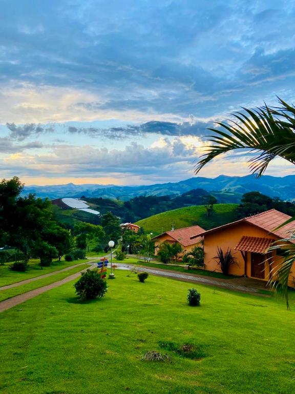 a green field with a house and a palm tree at Chalés Terras Altas in Gonçalves