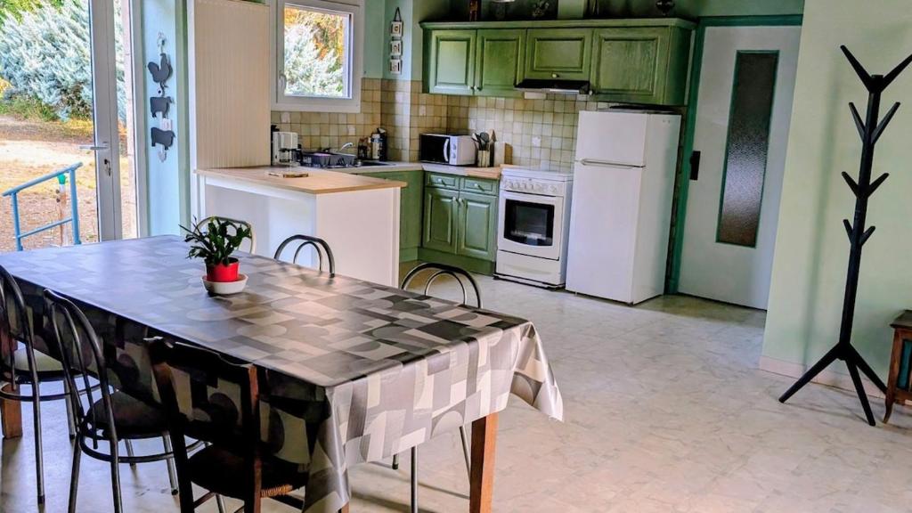 a kitchen with green cabinets and a table with chairs at Gîte en pierre maison quercynoise in Vaylats