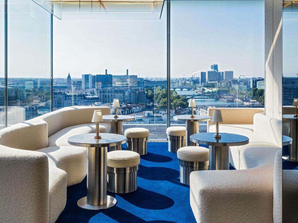 een bar met tafels en stoelen en uitzicht op de stad bij SO/ Paris Hotel in Parijs