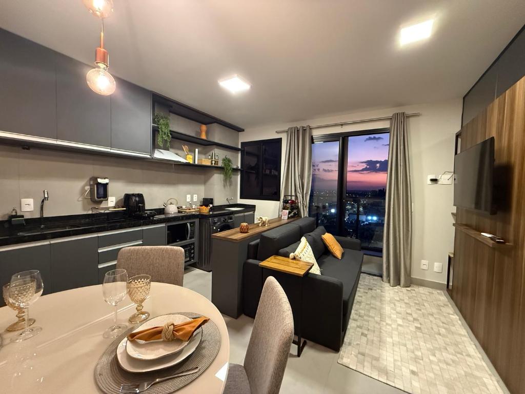 a kitchen and living room with a table and a couch at Apê Central Dourados in Dourados