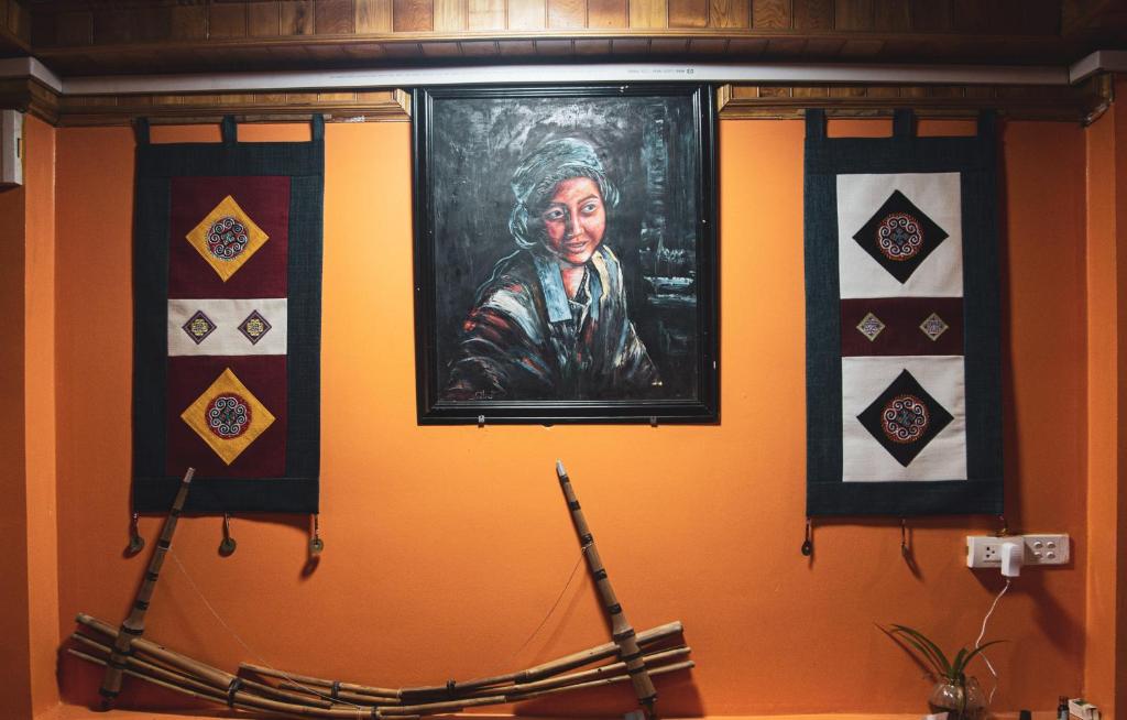 a painting of a woman on a wall with four quilts at Sapa Central House in Sa Pa
