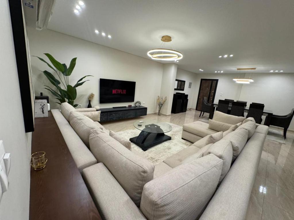 a living room with a large couch and a tv at Charming Apartment - Near Cairo Airport in Cairo