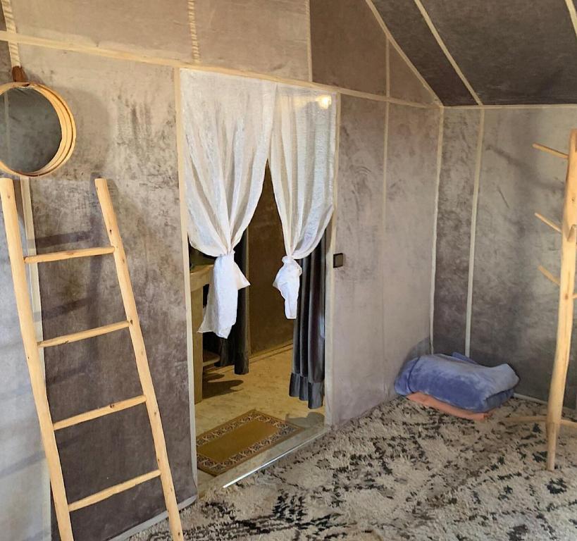 a room with a mirror and a ladder and a bed at Unique Luxury Camp in Merzouga