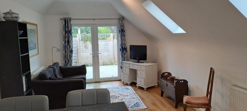 un salon avec un canapé et une télévision dans l'établissement Wren Cottage, à Hindhead