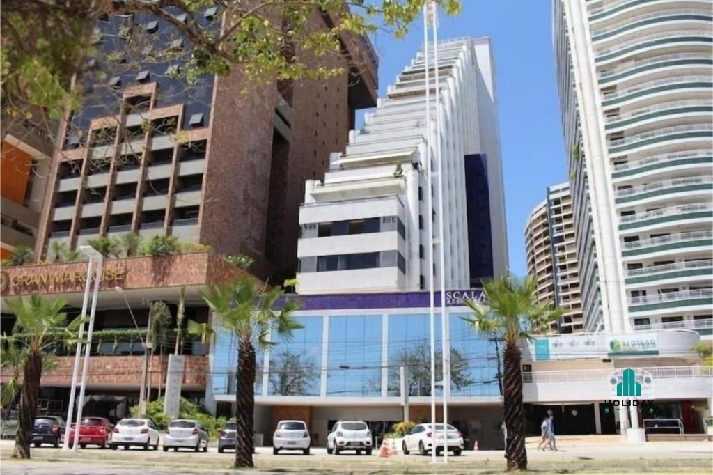 een hoog gebouw met palmbomen ervoor bij Scala Residenza By Holiday Stays in Fortaleza
