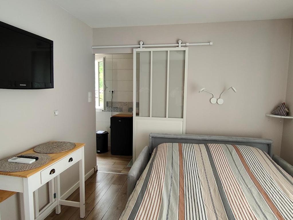 ピエルフ・デュ・バールにあるChambres d'hôtes au temps des cerisesのベッドと机とテレビのある寝室