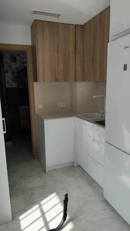 a kitchen with white cabinets and a white refrigerator at Urban relax in Dos Hermanas