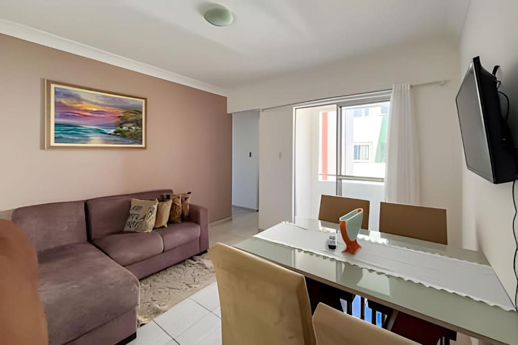 a living room with a couch and a table at Apto com AR, 3/4 em condomínio com piscina e lazer in Aracaju