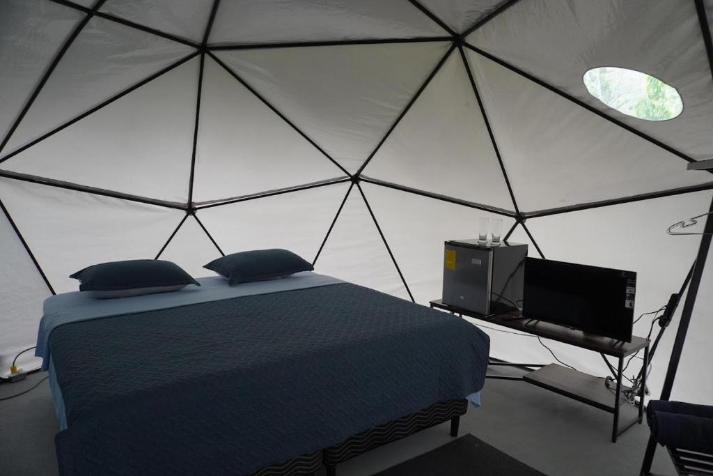 a bedroom with a tent with a bed and a tv at Osaglamping in Palmar Norte