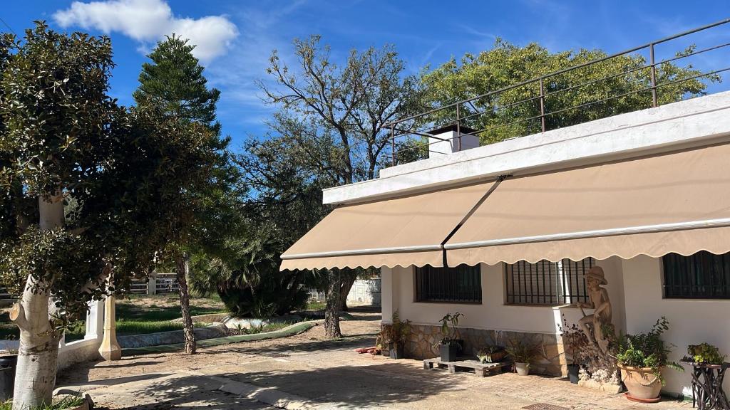 MatolaにあるCa Didiの木々の隣にある黄褐色の日よけのある建物