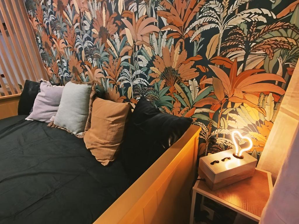 a couch in a room with a tropical wallpaper at Joli studio à Aix-en-Provence in Aix-en-Provence