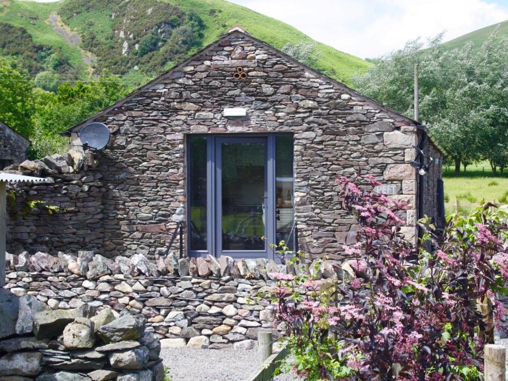 a small stone house with a stone wall at 1 Bed in Ullswater 94068 in Watermillock