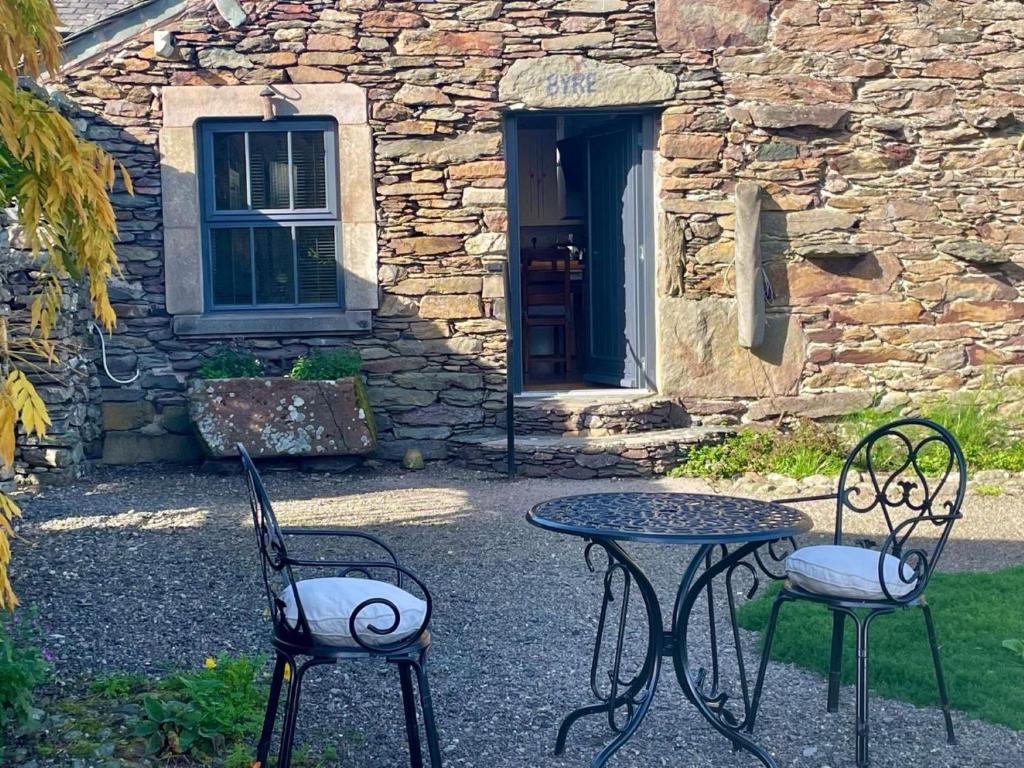 two chairs and a table in front of a stone building at 1 Bed in Ullswater 94066 in Watermillock