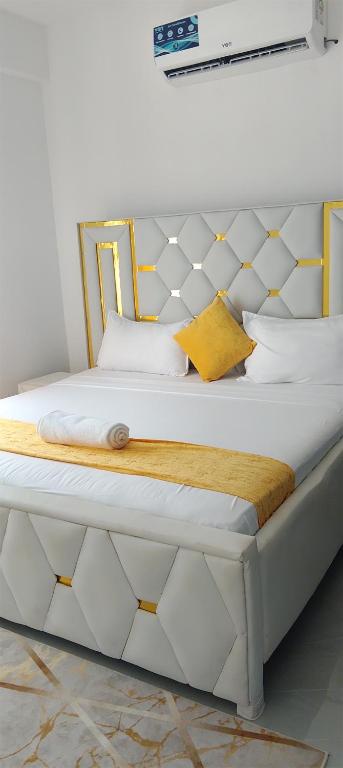 una cama blanca con cabecero blanco y dorado en AQUA GARDENS SEAVIEW LUXURIOUS HOMESTAY NYALI Msa, en Mombasa