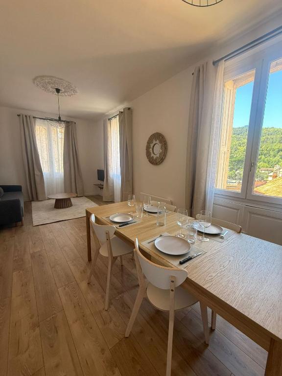 ヴェルネ・レ・バンにあるAppartement de charme et lumineux, 2 chambresのダイニングテーブルと椅子、そして大きな窓