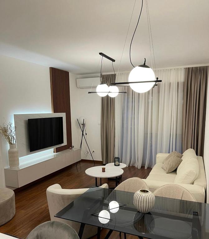 a living room with a white couch and a tv at StayPoint Apartment in Podgorica