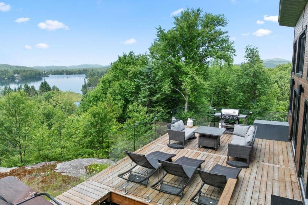 a deck with furniture and a view of a lake at Laurentides Scandinavian Chalet with Jacuzzi and Lake in Sainte-Lucie-de-Doncaster