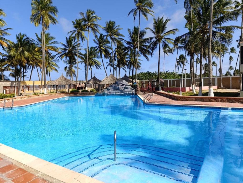 ein großer Swimmingpool mit Palmen im Hintergrund in der Unterkunft Apartamento con vista al mar Tucacas in Tucacas