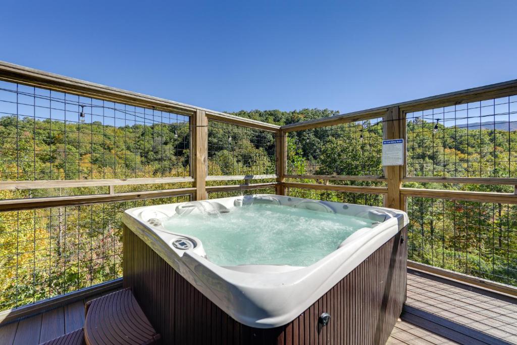 Una bañera en un balcón con vista al bosque. en Game Room, Hot Tub, Pool and Views Gatlinburg Cabin, en Gatlinburg