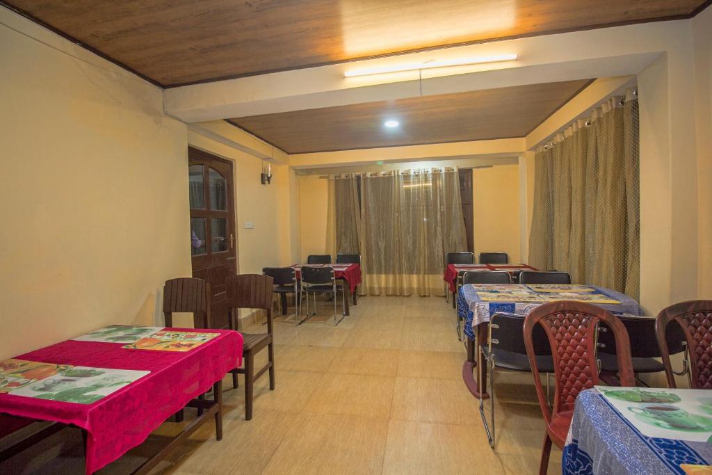 a dining room with tables and chairs with red table cloth at Hotel O Tashi Norling Ridge Park in Gangtok