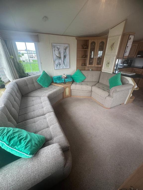 ein Wohnzimmer mit einem Sofa und grünen Kissen in der Unterkunft Meadow view 93 8 berth Chapel, Skegness SANTANAVAN 15 in Chapel Saint Leonards