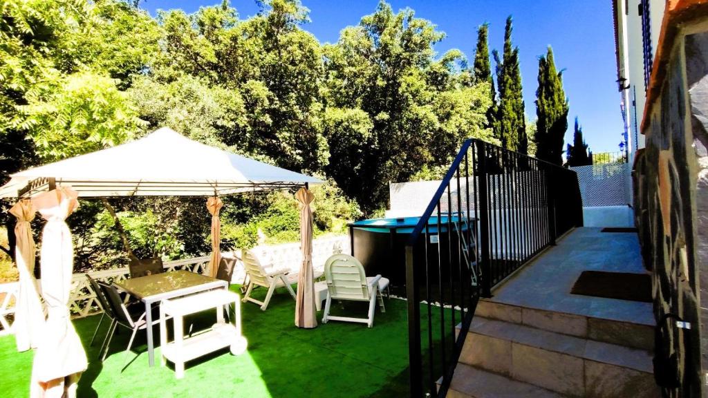 a patio with a table and chairs and an umbrella at Casa Rural Arrebol - Barbacoa y piscina in Aracena