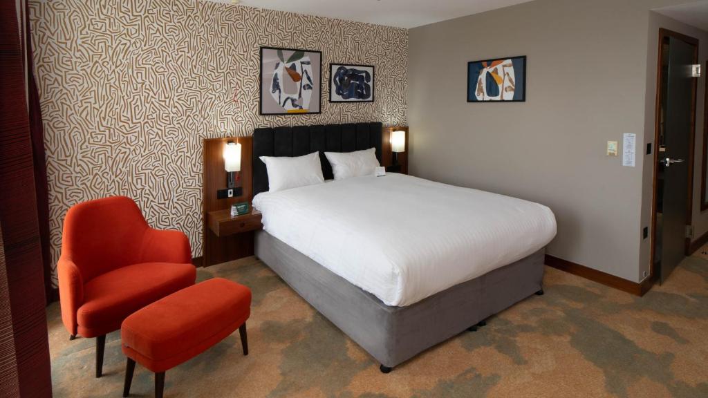 a bedroom with a bed and a red chair at Holiday Inn Bristol City Centre by IHG in Bristol