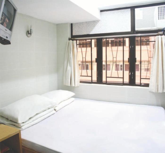 Habitación blanca con cama y ventana en Pearl Guesthouse - 6/F, en Hong Kong