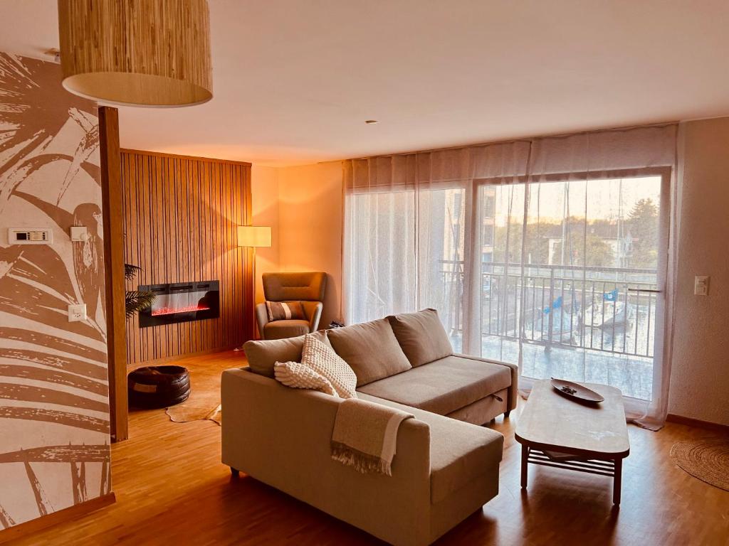 a living room with a couch and a large window at Loft Cosy sur le Lac in Bouveret