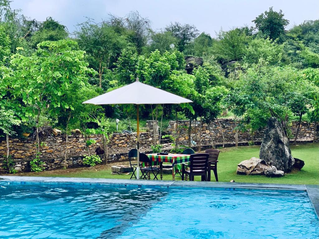 a table and chairs under an umbrella next to a swimming pool at Sayar Bagh Jawai in Nāna