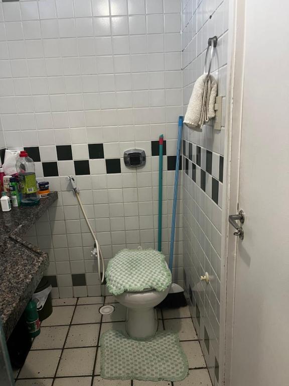 a bathroom with a toilet with a green lid at Quarto a 10m da praia ao lado de Pubs e Restaurantes in Recife