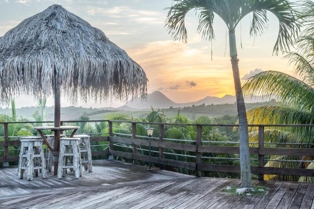 eine Terrasse mit einem Tisch und zwei Hockern und einer Palme in der Unterkunft La Villa Cocoon prestige et vue mer in Sainte-Luce