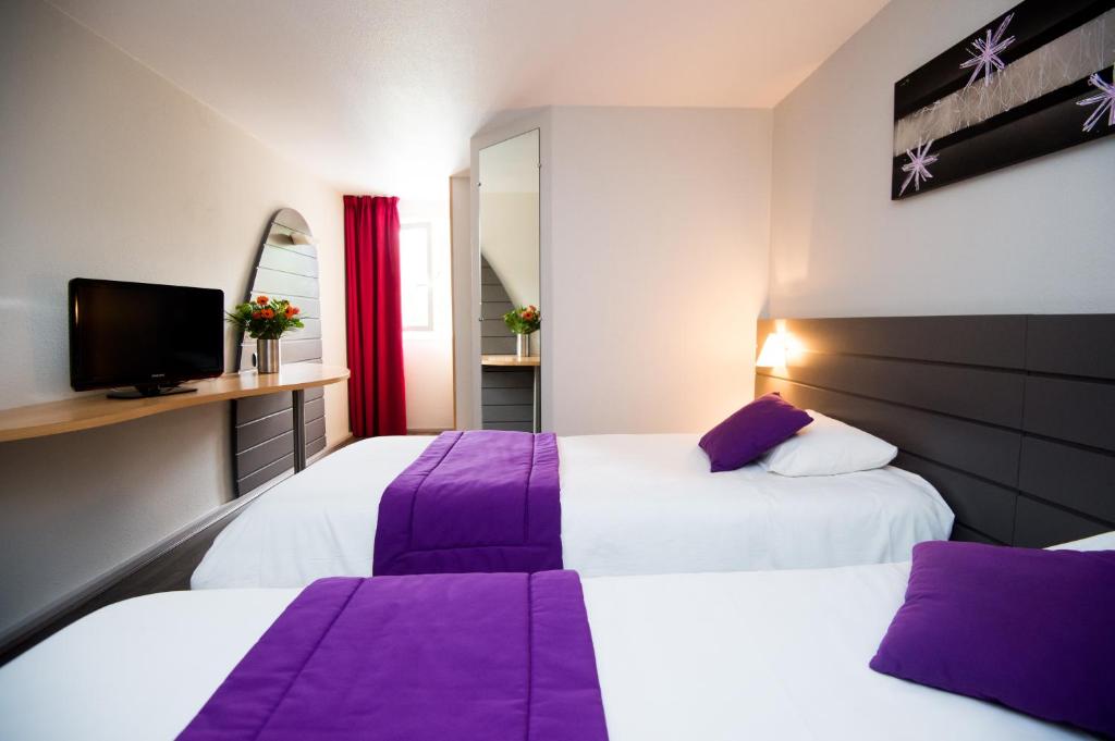 two beds in a hotel room with purple sheets at Kyriad Orthez in Orthez