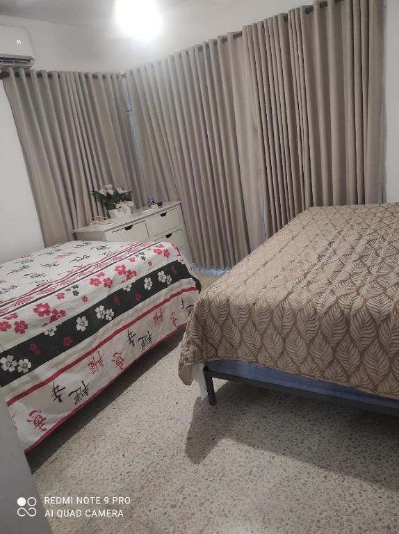 a bedroom with a bed and a dresser and curtains at Sweet beach apartment in San Felipe de Puerto Plata