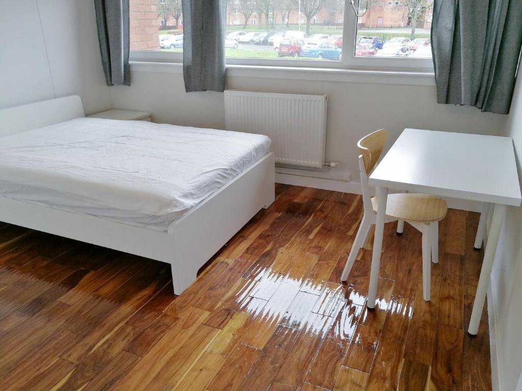 een slaapkamer met een bed, een bureau en een tafel bij Woodside room Glasgow in Glasgow