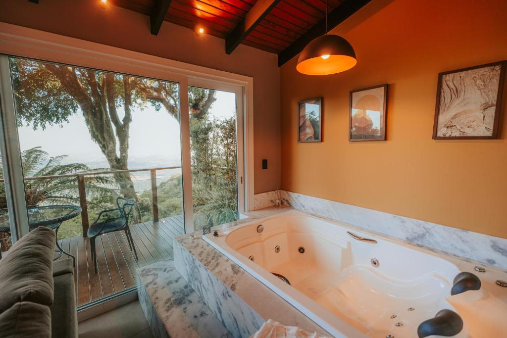 a large tub in a room with a large window at Cabana romântica com Jacuzzi ao lado de Gramado in Igrejinha