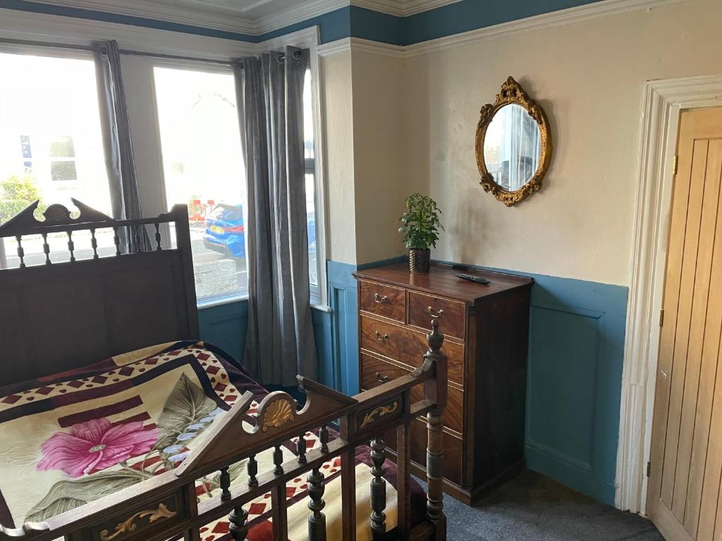 a bedroom with a bed and a dresser and a mirror at PERiVALE LODGE in Folkestone
