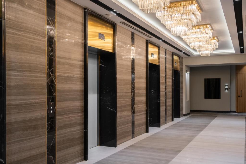 a row of glass doors in a hallway with chandeliers at Nest One Luxe, Элитные апартаменты с балконом и видом на фонтан Tashkent City Park 110 in Tashkent