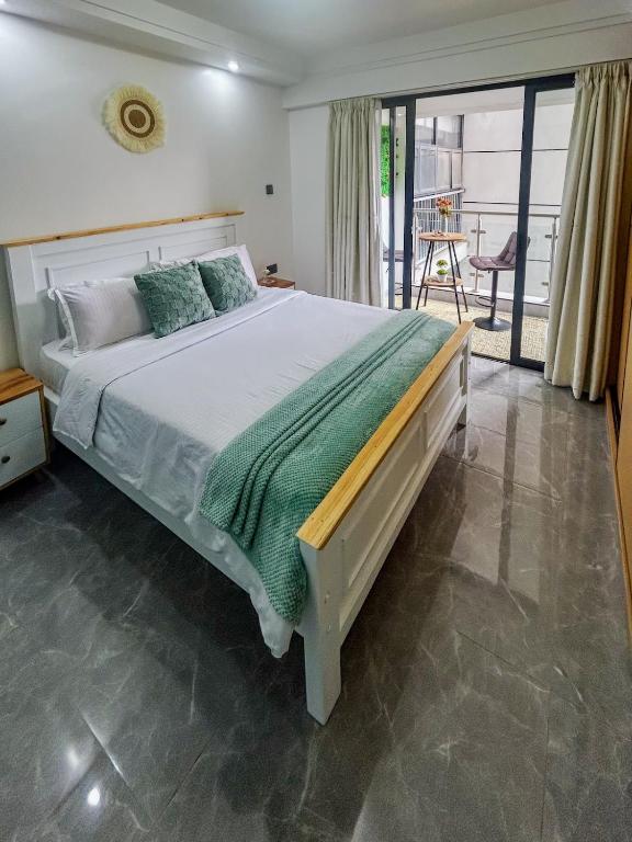 a bedroom with a large bed and a balcony at Urban Shell Retreat- Kileleshwa in Nairobi