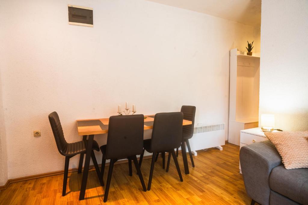 a dining room table with black chairs and a couch at Apartman Gnječ Kupres in Kupres