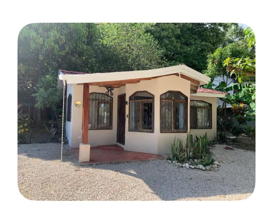 una pequeña casa con una puerta en un patio en Oceana Breeze Perfect Getaway steps from the beach, en Sámara