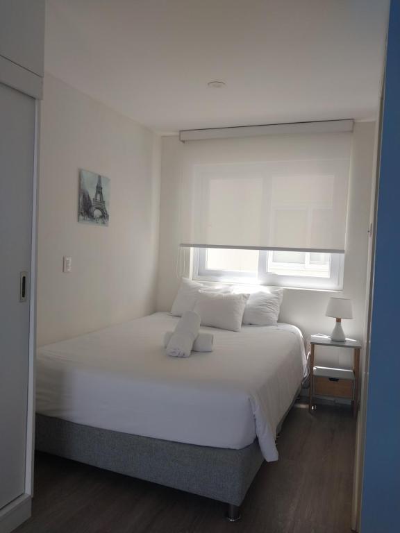 Un dormitorio con una cama blanca y una ventana. en Quark Apartments, en Lima