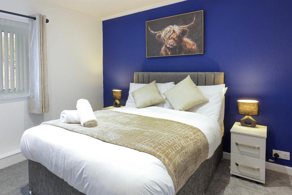 a bedroom with a large bed with a blue wall at Duffus Nights in Duffus