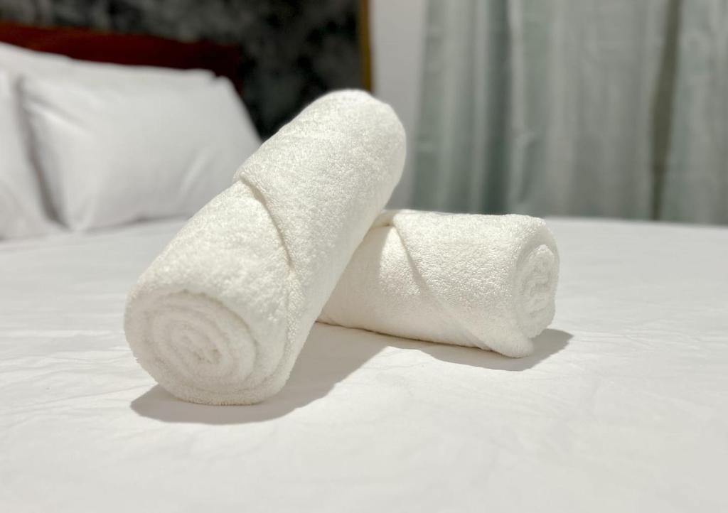 two rolls of white towels sitting on a bed at Pousada Aimê Maresias in São Sebastião