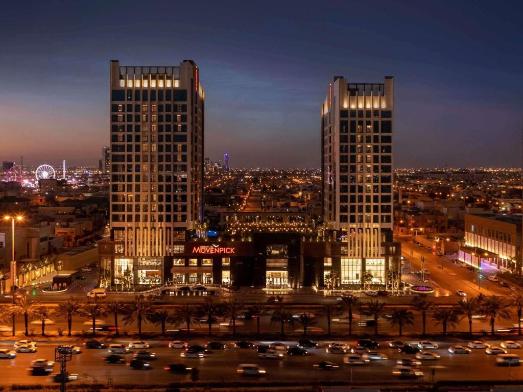 リヤドにあるMovenpick Hotel and Residences Riyadhの夜の街にある2つの高層ビル