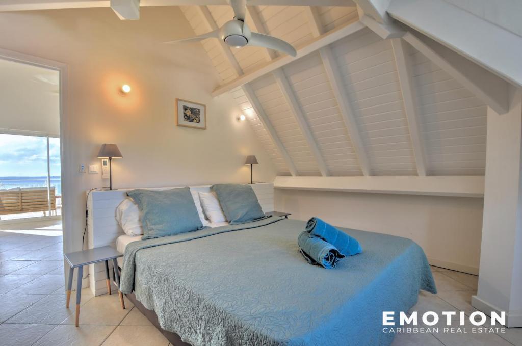 ein Schlafzimmer mit einem Bett mit einer blauen Bettdecke in der Unterkunft Deux pièces sur la belle plage de Grand Case in Grand Case