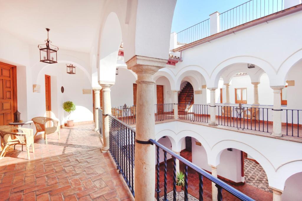 un edificio con paredes blancas y una escalera con mesas y sillas en Apartamentos Casa del Aceite, en Córdoba